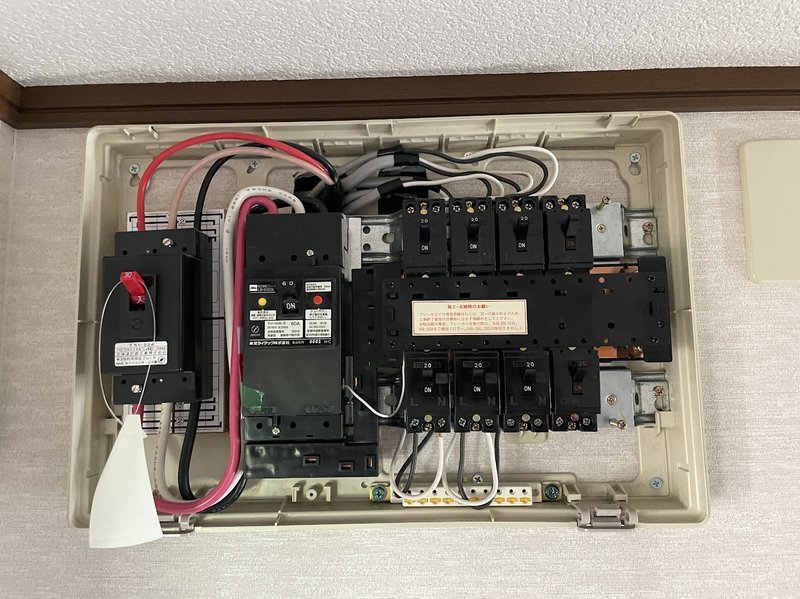 分電盤のカバーを外して撮影したエアコン専用回路完成の様子（注意書きラベル付き）