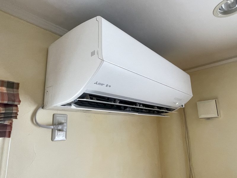 完成：室内機の左下に増設した200Vコンセント。以前はコンセントが壁のボード内に埋まっていた