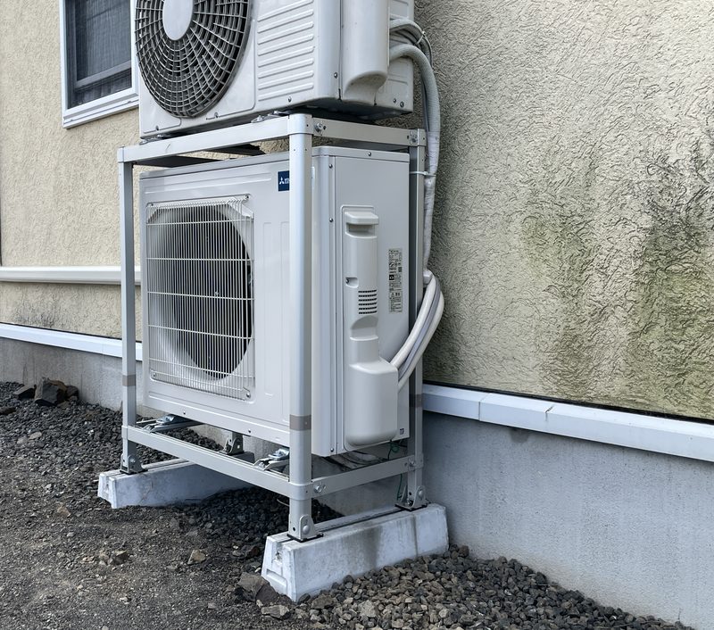 完成：2段架台の下段にほとんど隙間なく収まった室外機。足が引っかかるのを斜めにしながら押し込んだ